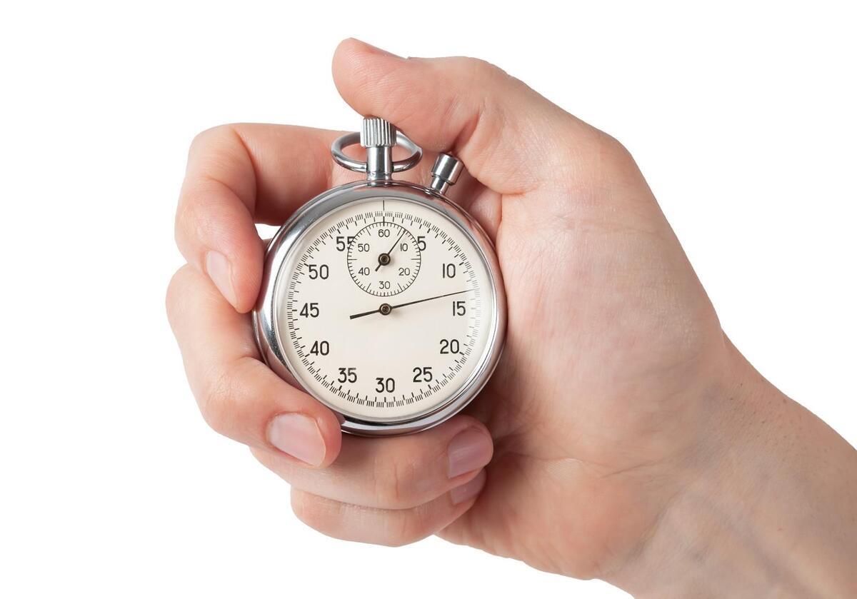 Close up of hand holding stopwatch, isolated on white background