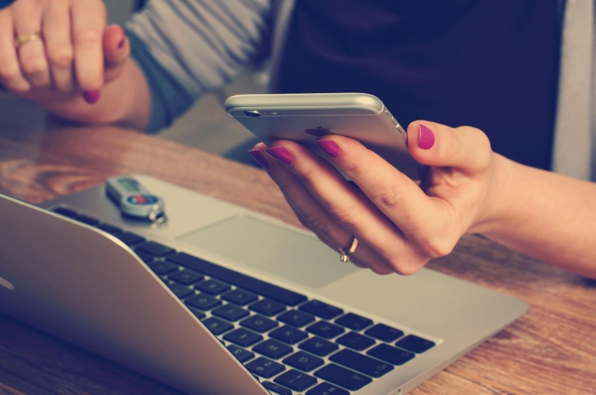 person using a phone and a laptop